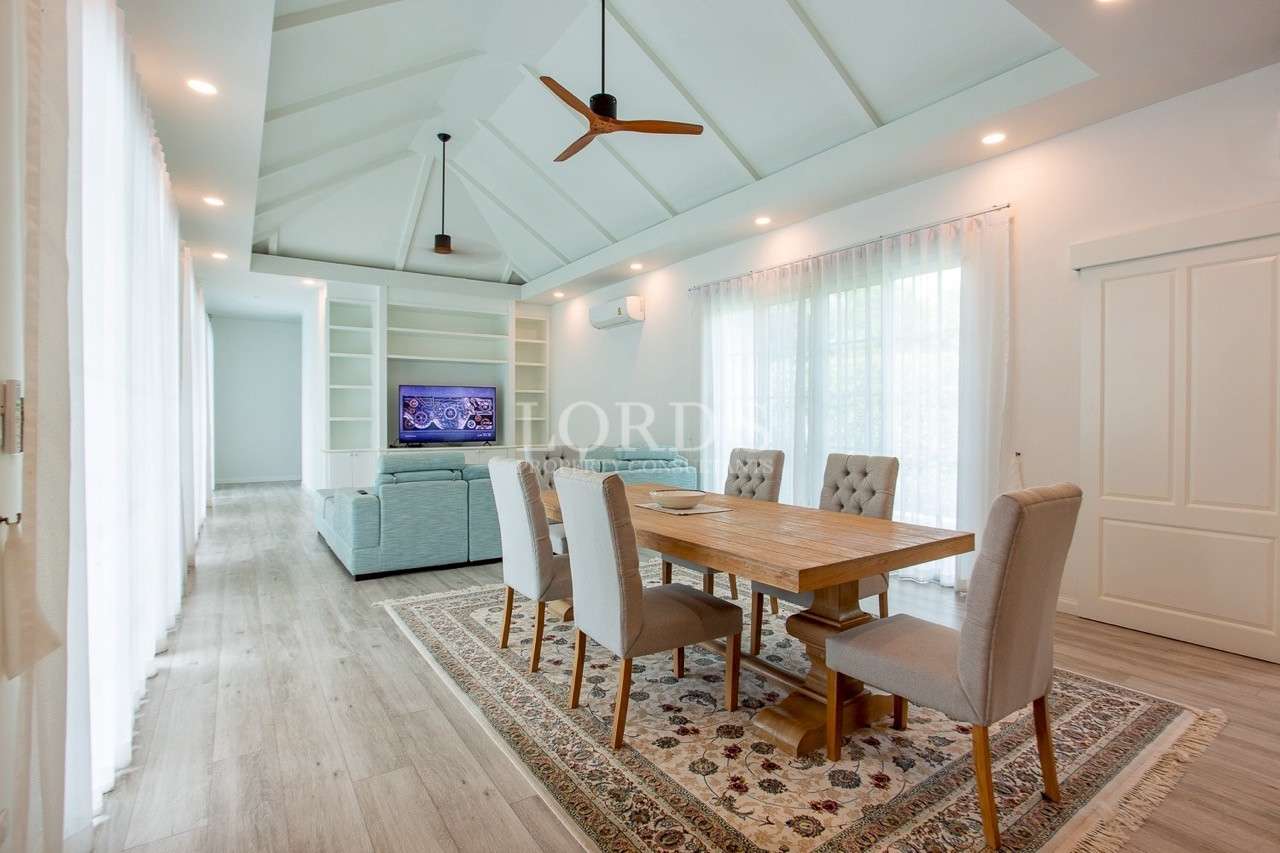 Open-plan dining and living area with high vaulted ceiling and wooden dining table