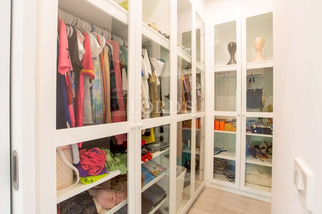 Walk-in closet with glass door wardrobes and built-in shelves