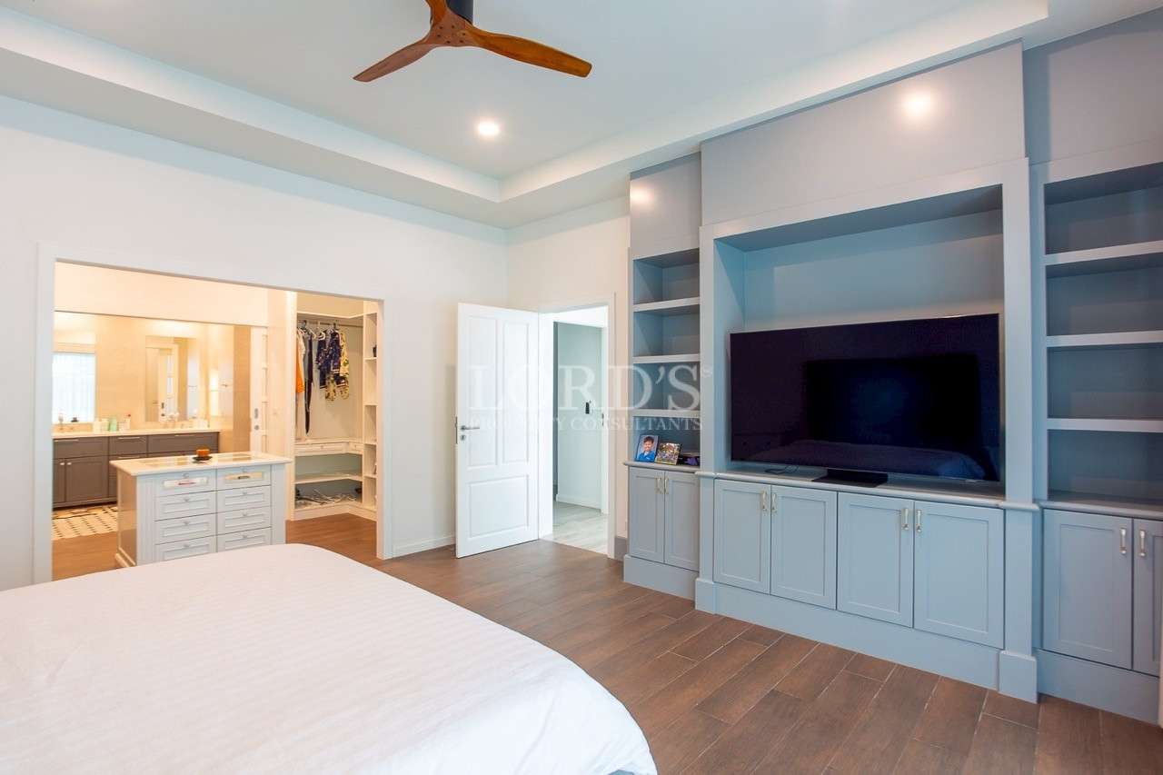 Spacious master bedroom with built-in TV cabinet and walk-in closet