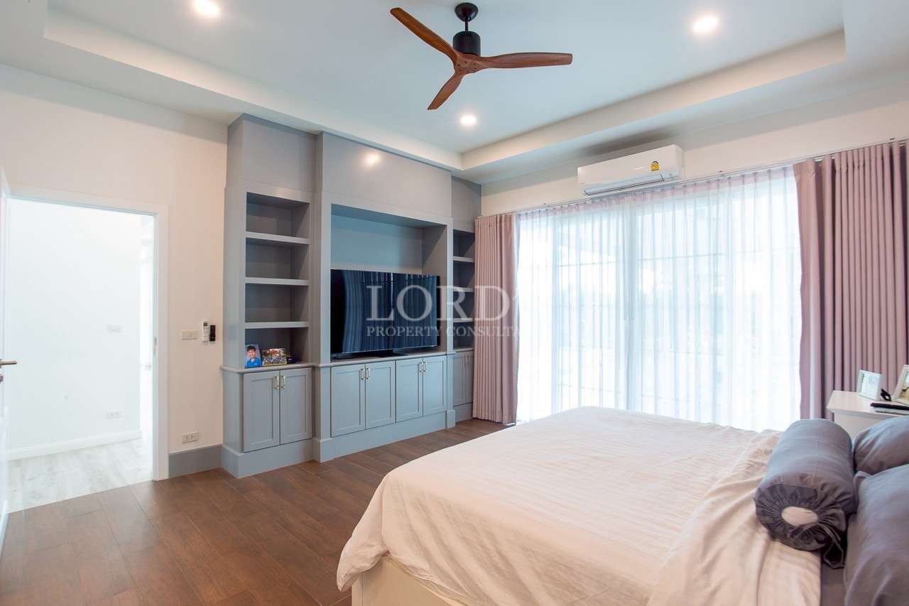 Modern bedroom with built-in TV cabinet, large window, and ceiling fan