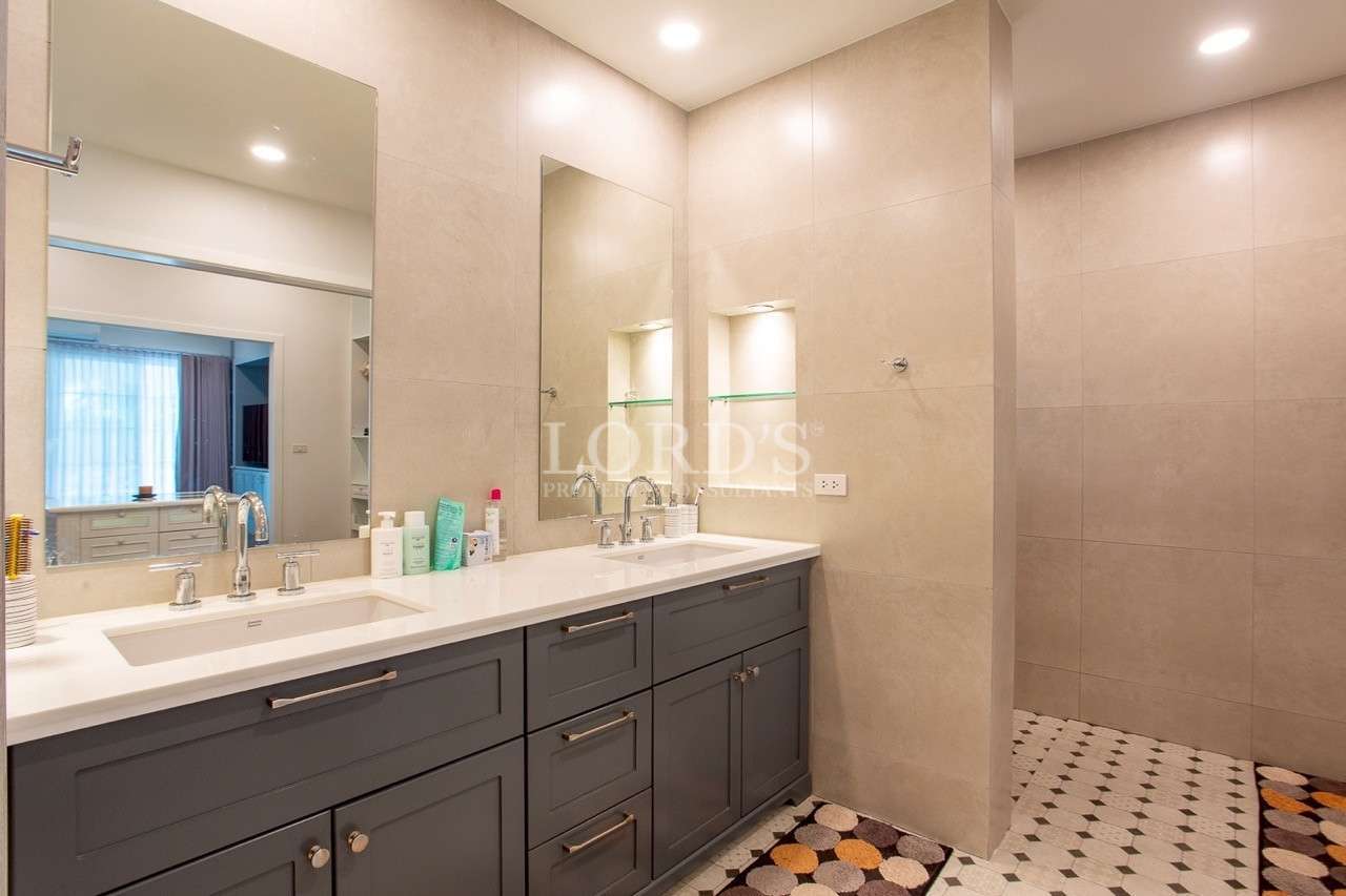 Modern double vanity bathroom with beige tiles and walk-in shower.