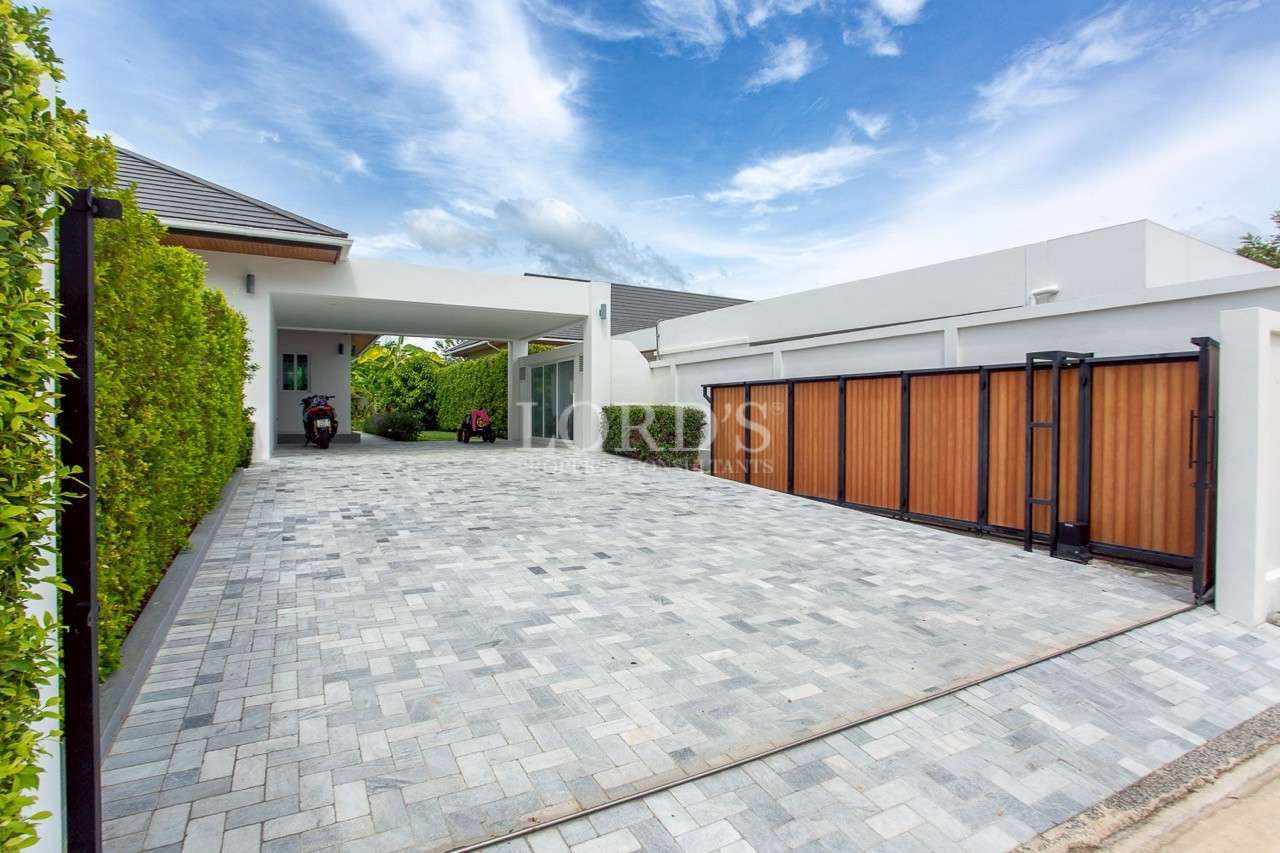 Large modern driveway with sliding wooden gate and covered carport.