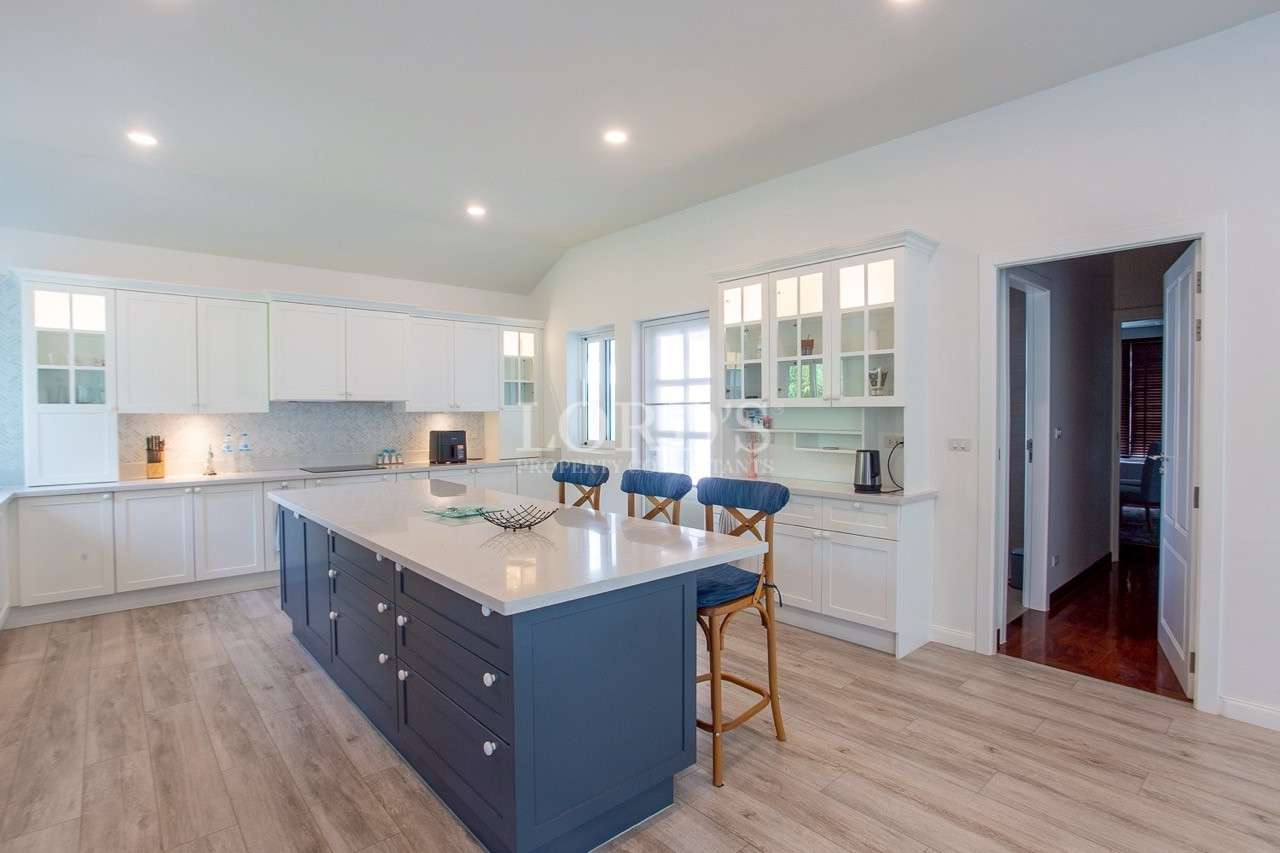 Bright modern kitchen with large blue island, white cabinets, and bar stools.