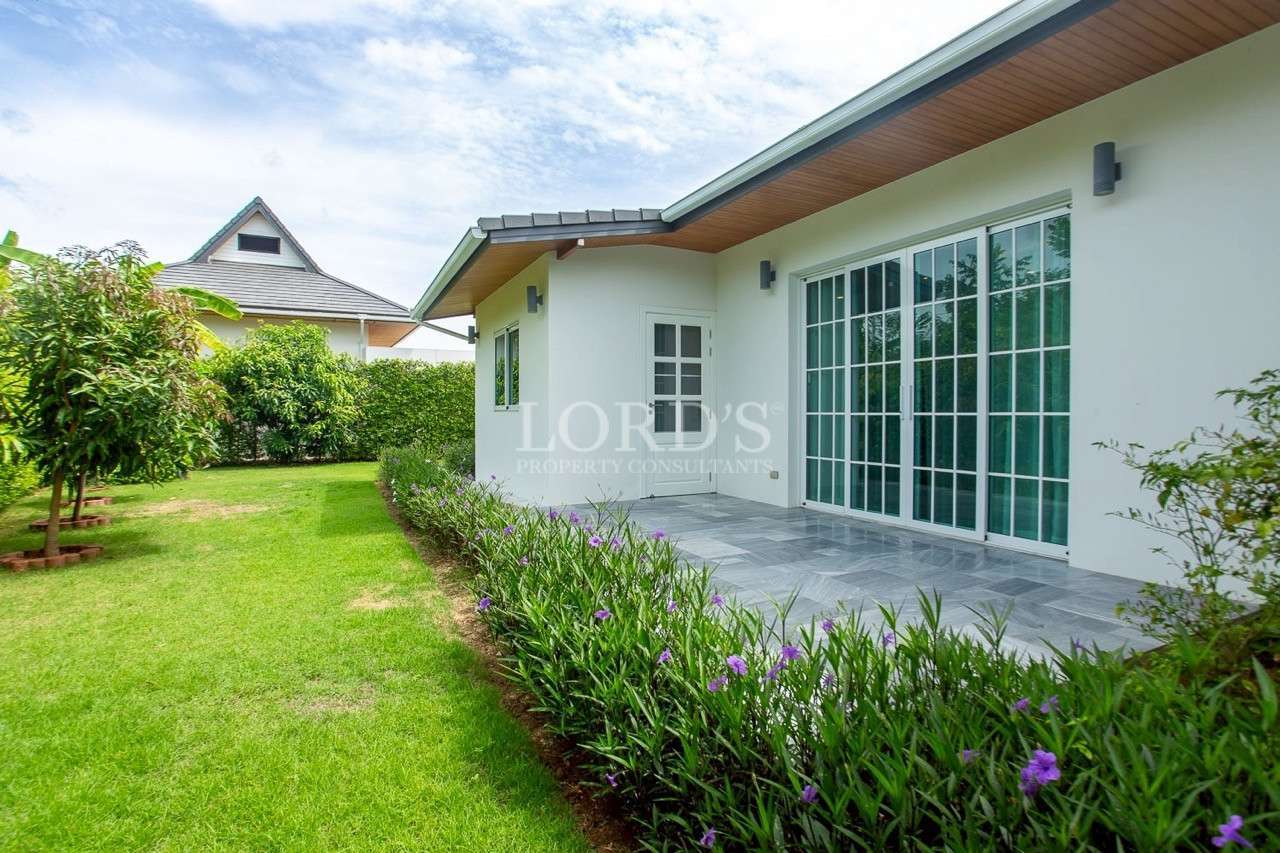 Modern white villa exterior with sliding glass doors and landscaped garden.