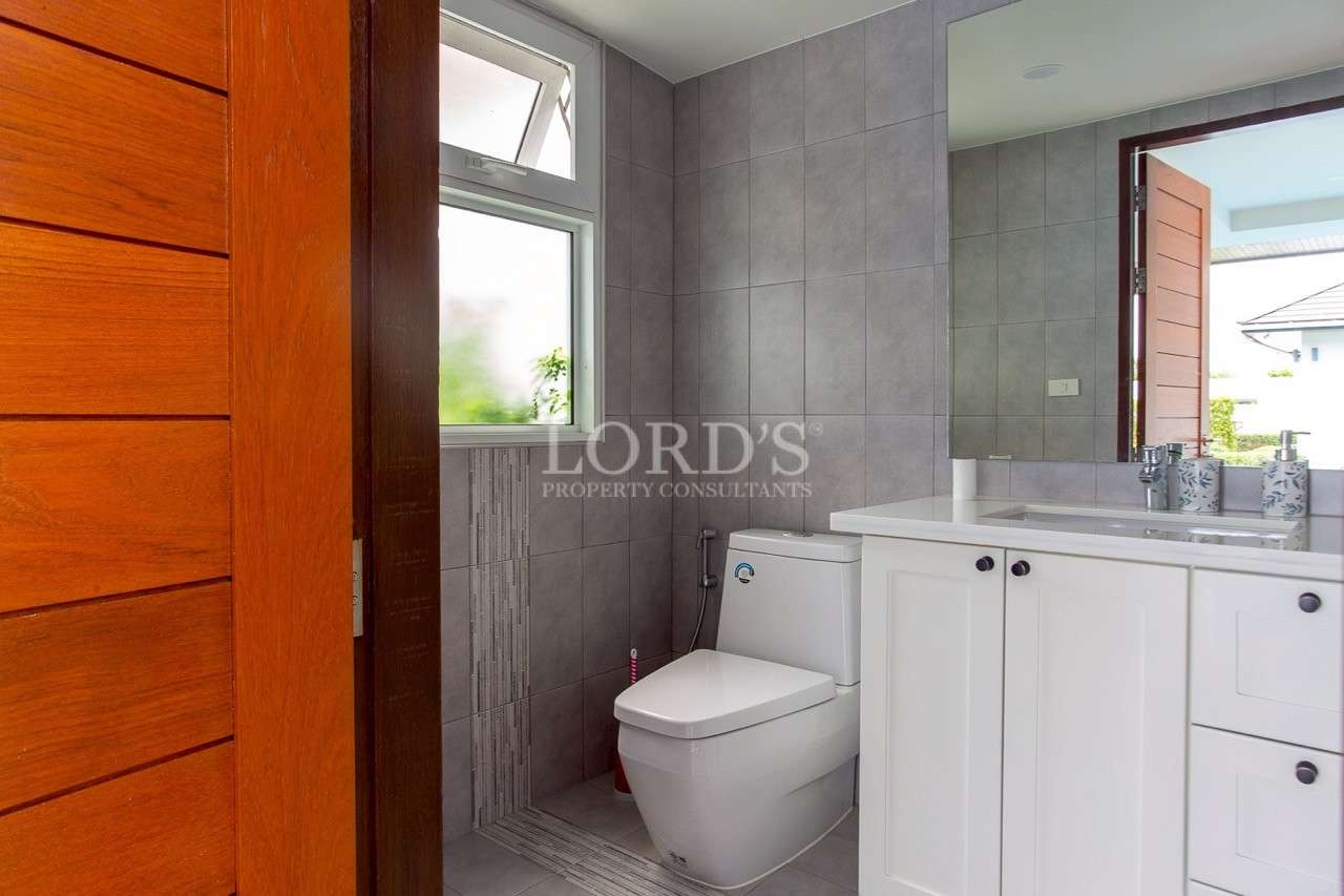 Modern bathroom with gray tiled walls, white vanity cabinet, and compact toilet.