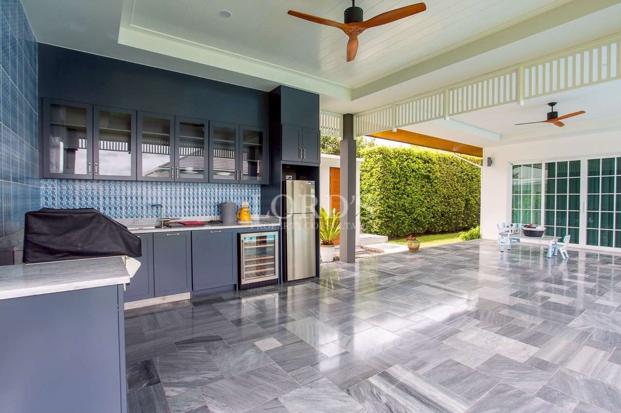 Covered outdoor kitchen and patio area with modern cabinets and tiled flooring.