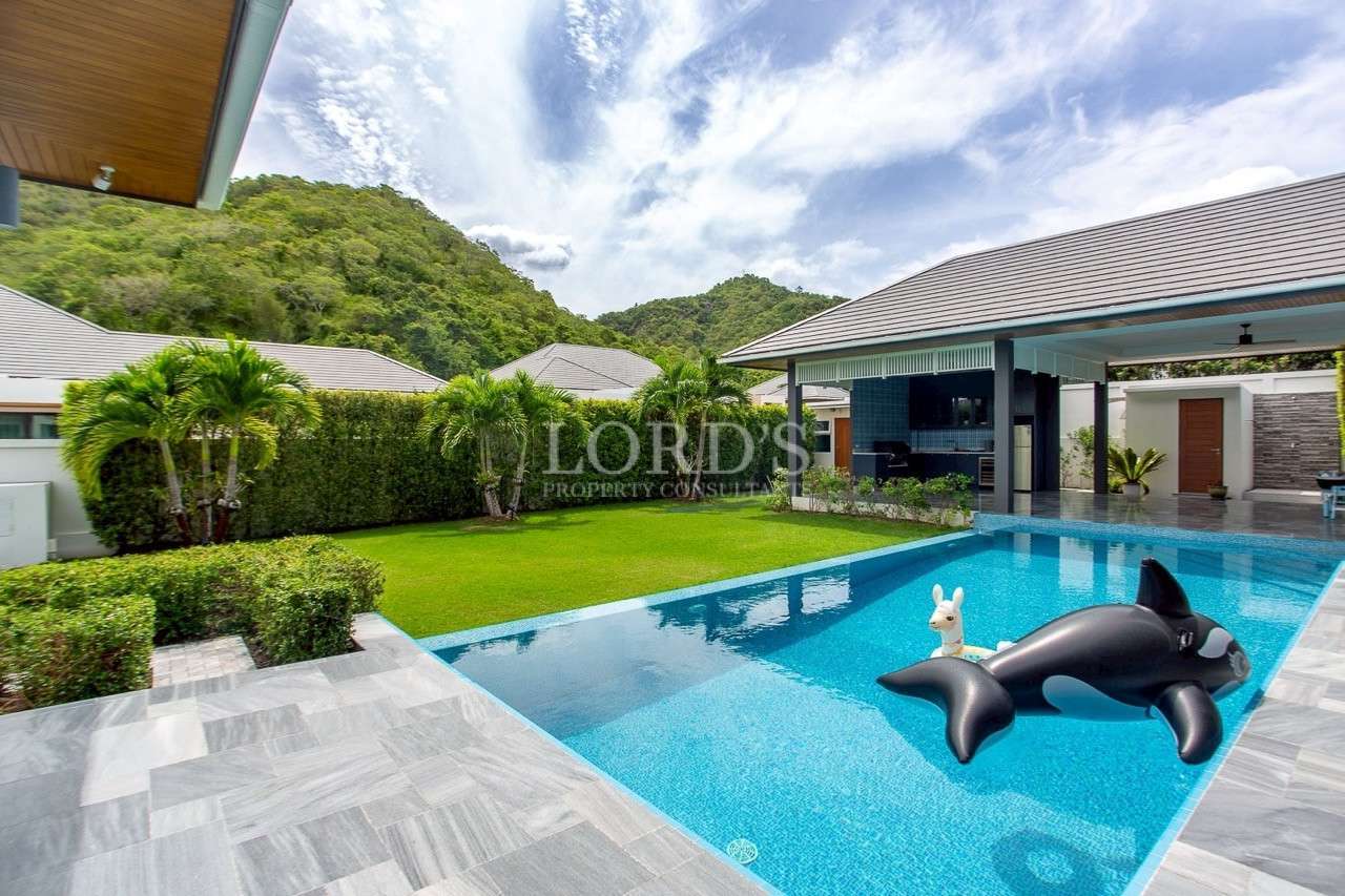 Modern villa backyard with private swimming pool, green lawn, and inflatable orca float.