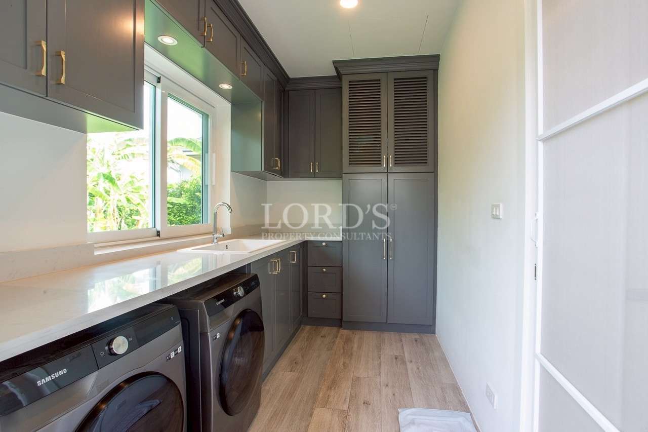 Modern laundry room with gray cabinets, front-load washer and dryer, sink, and window.
