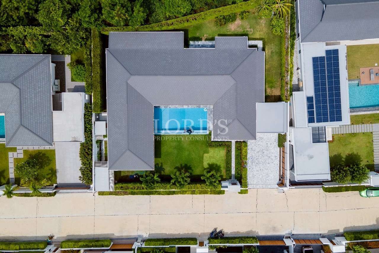 Aerial top-down view of modern villa with central courtyard pool and landscaped garden.