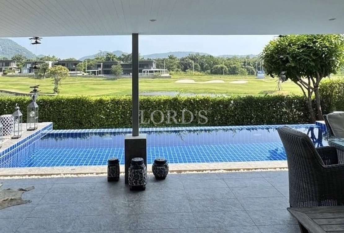 Covered terrace overlooking a private swimming pool with golf course and mountain views beyond.