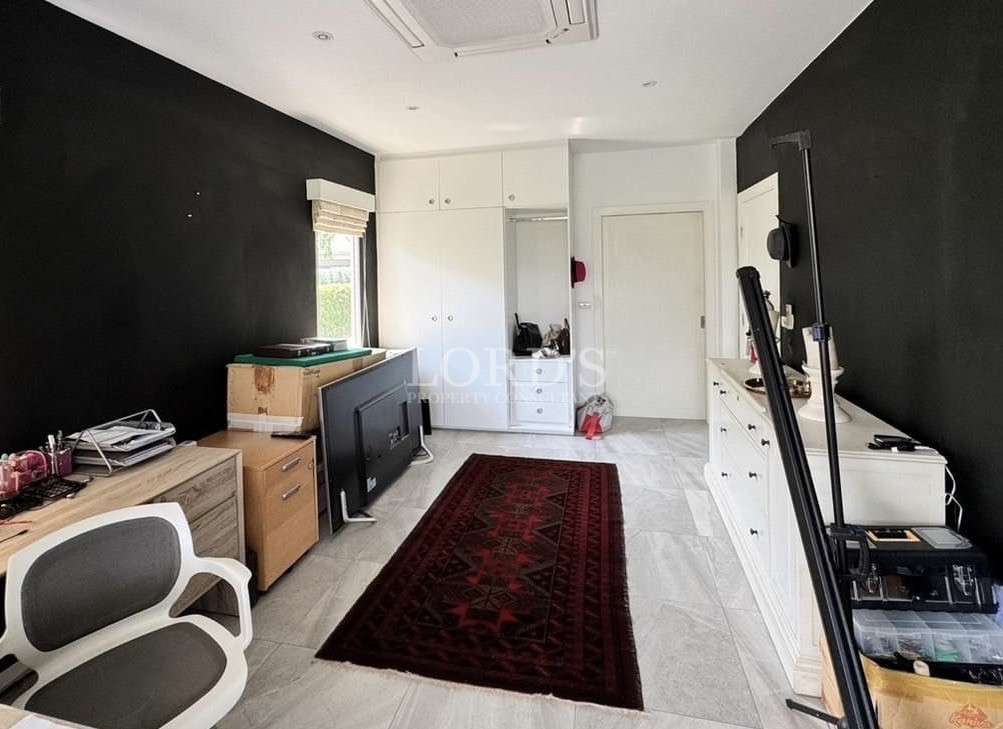 Multi-purpose room with dark accent walls, storage cabinets, workspace furniture, and area rug.