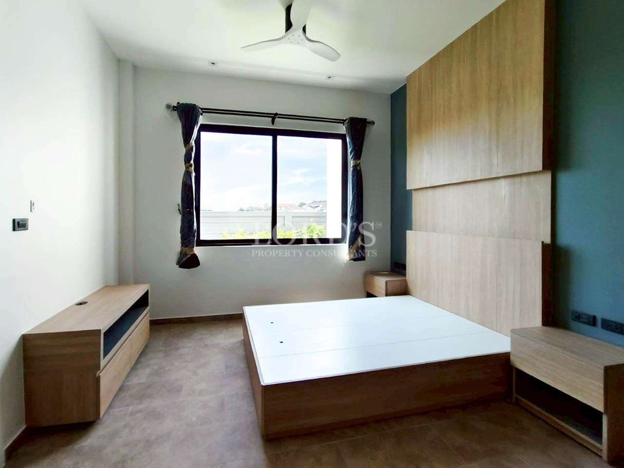 Bright modern bedroom with wooden bed frame, large window, and ceiling fan.