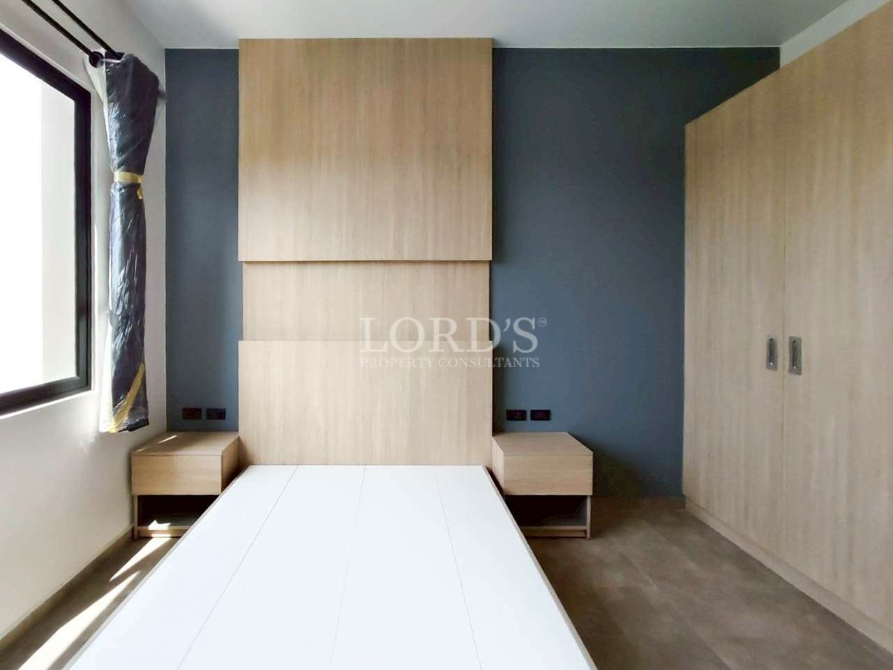Modern bedroom with built-in wardrobe, wooden bed frame, and bedside tables.