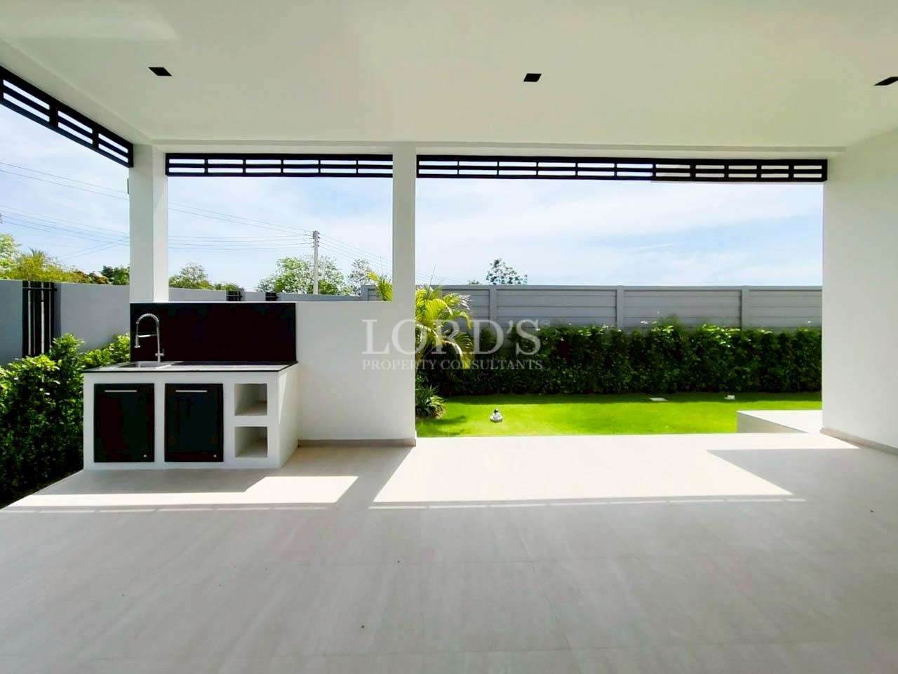Covered outdoor terrace with built-in sink and open view of the green garden.