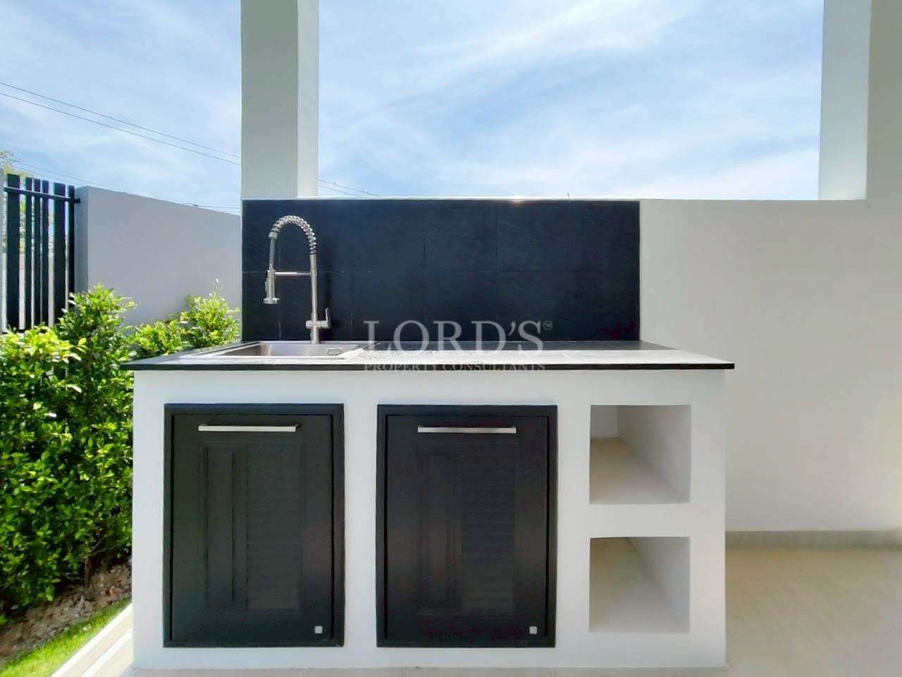 Outdoor kitchen sink and counter on a covered terrace next to the garden.
