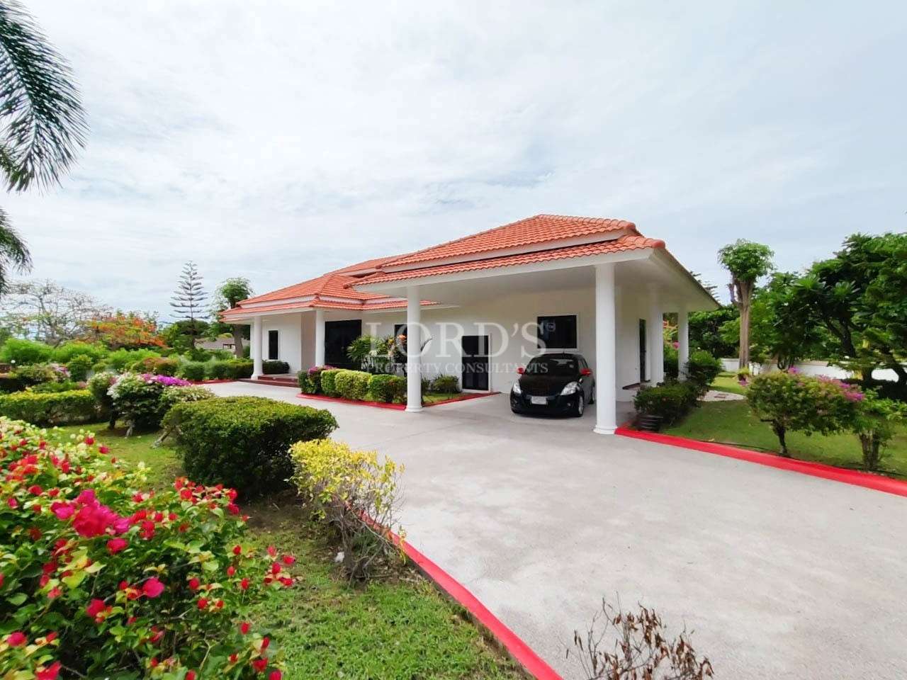 Luxury villa with covered carport, landscaped garden, and driveway