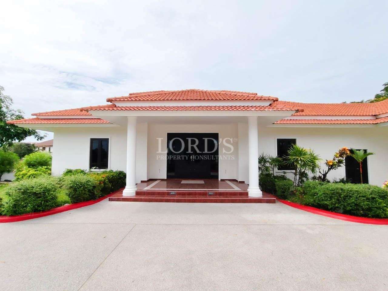 Front view of luxury white villa with red tile roof and columns