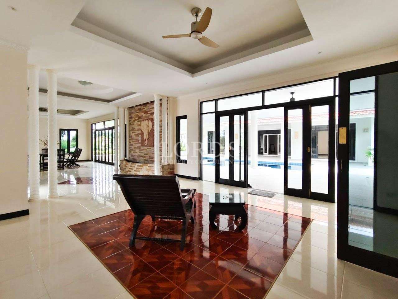 Luxury villa living area with glass doors, white columns, and pool view
