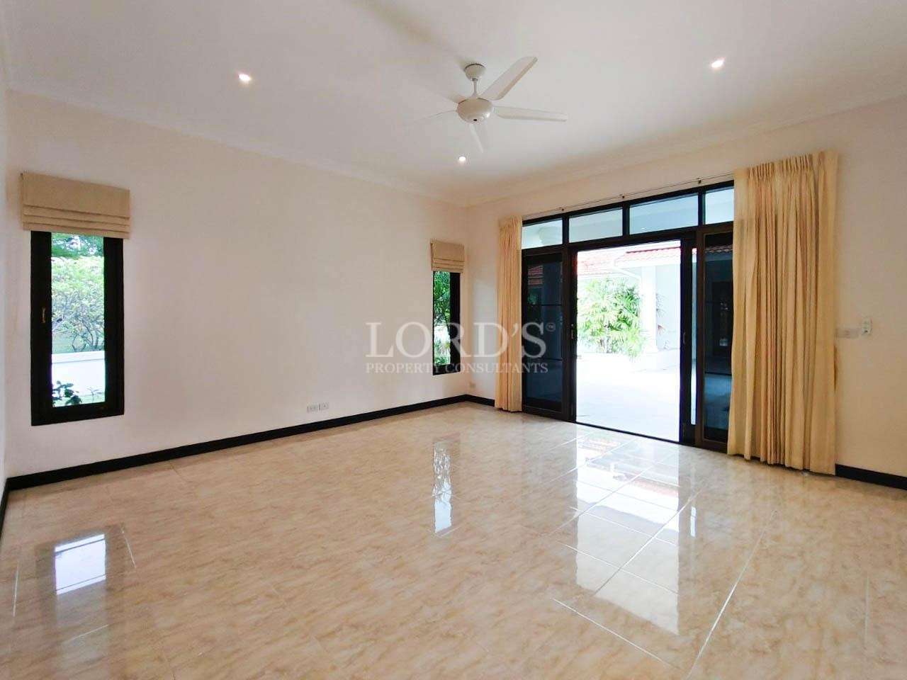 Spacious empty bedroom with glossy tile floor, ceiling fan, and sliding glass doors