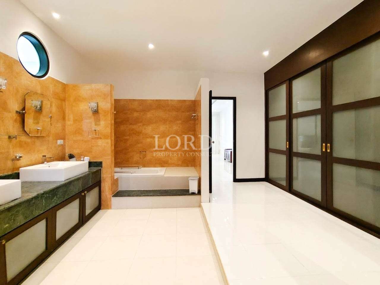 Modern luxury bathroom with double vanity, bathtub, and sliding wooden closet doors