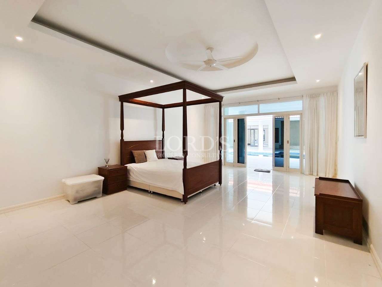 Spacious modern bedroom with wooden four-poster bed and sliding glass doors