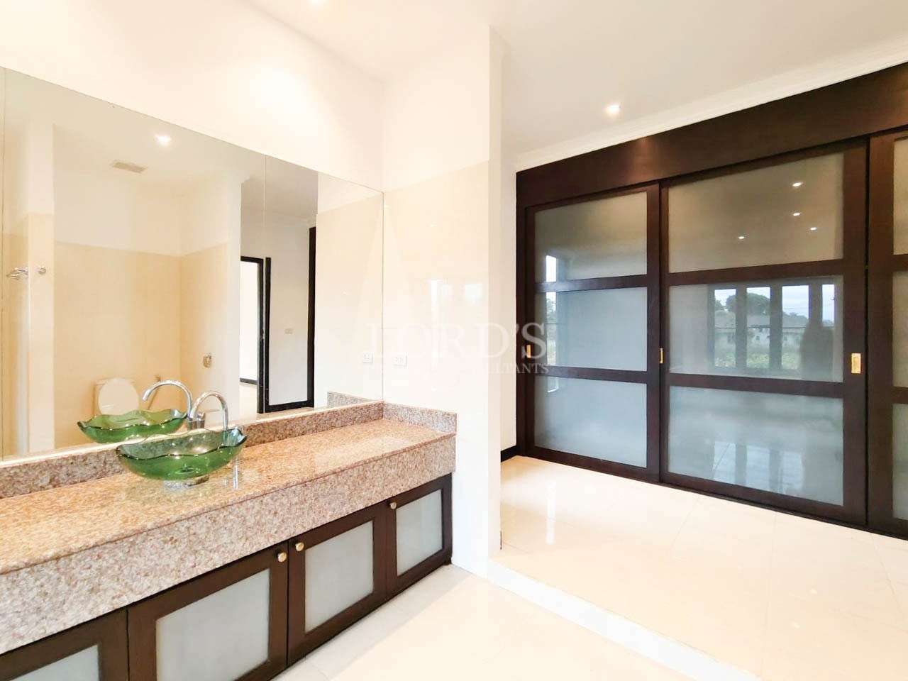 Modern bathroom with granite double vanity, green glass sinks, and sliding wooden doors