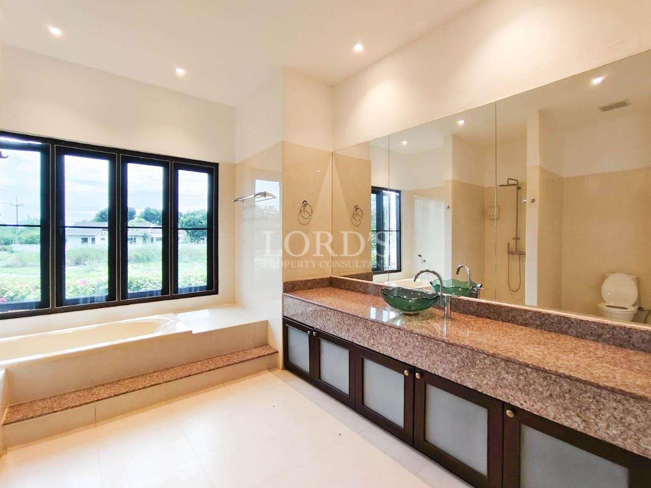 Luxury modern bathroom with bathtub, granite countertop, double sink, and large mirror