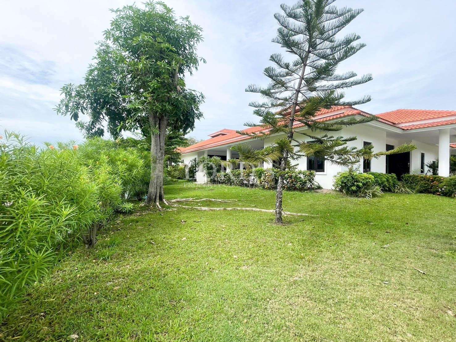 Luxury villa with landscaped garden, green lawn, and red tiled roof