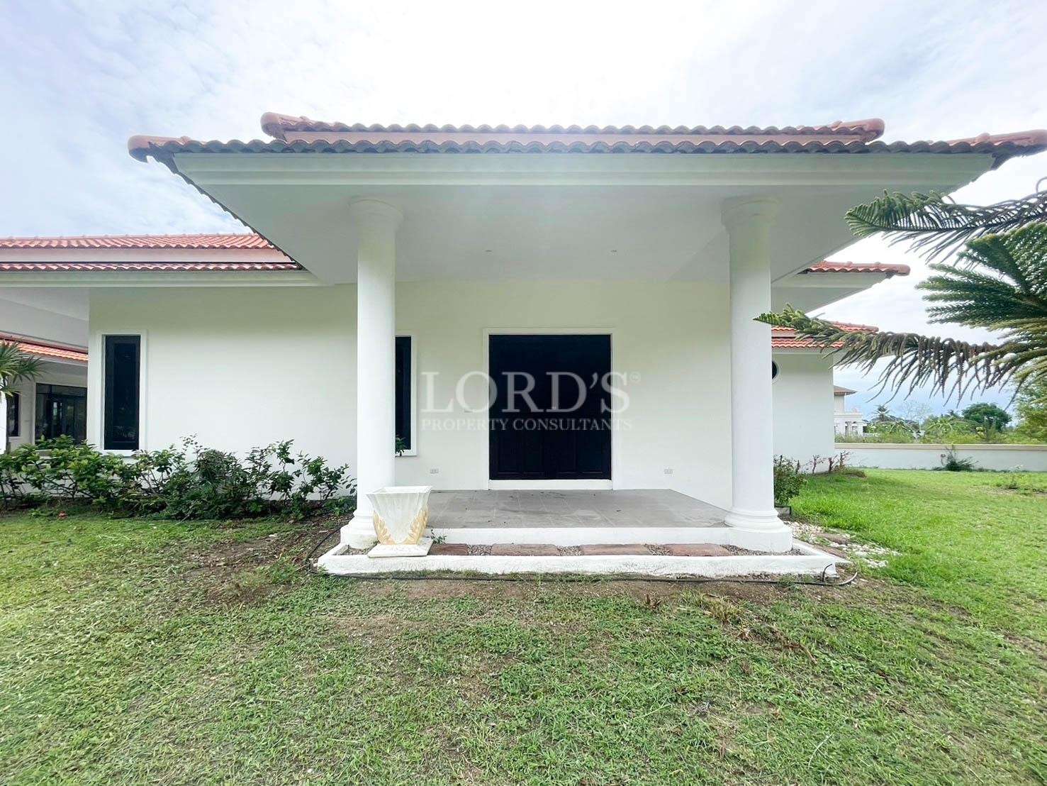 Modern villa entrance with white columns, red tiled roof, and small front porch