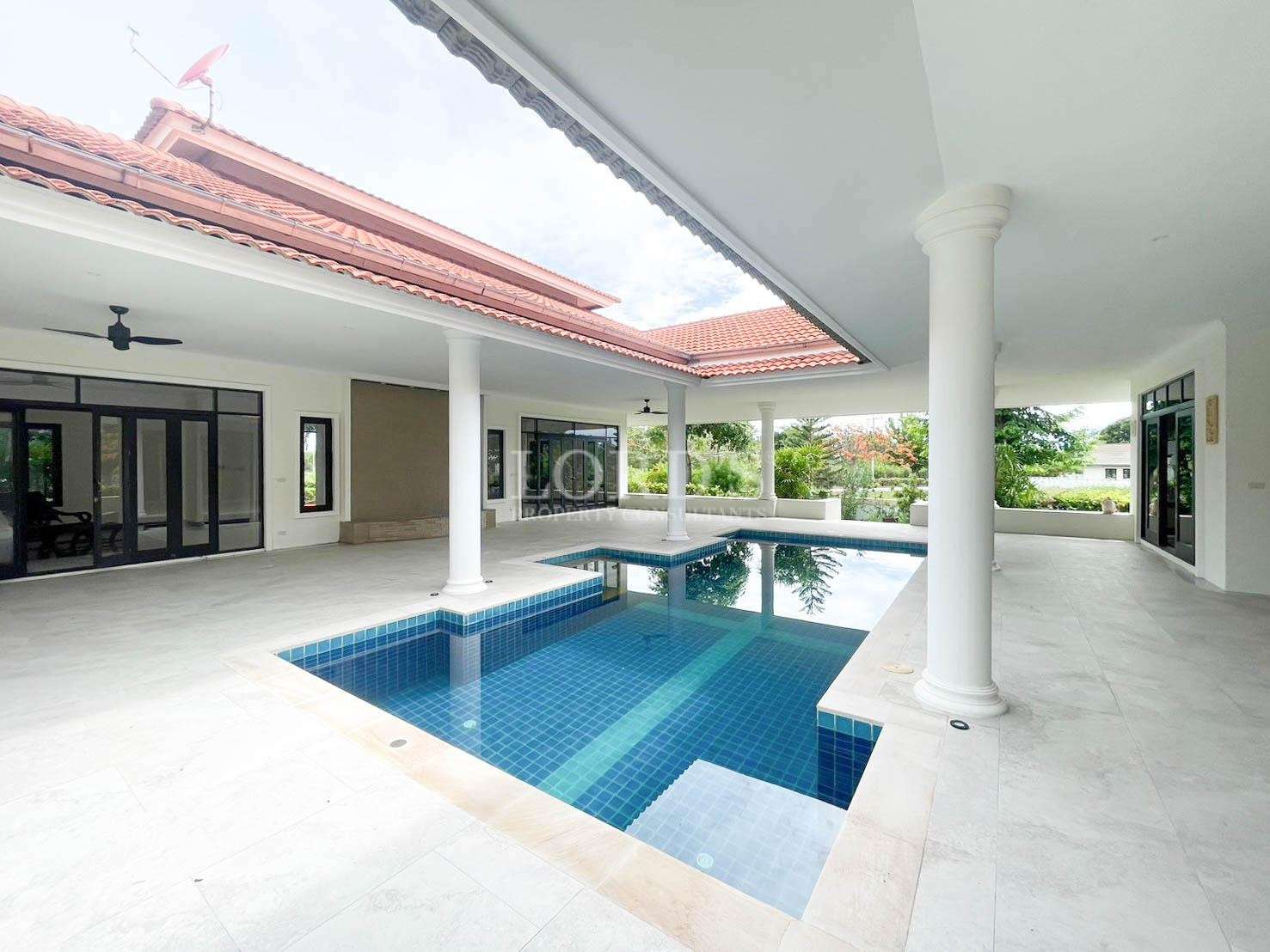 Modern luxury villa with covered courtyard pool, white columns, and red tiled roof