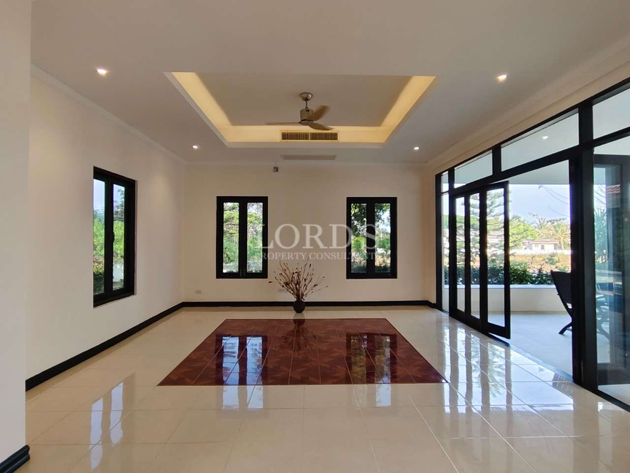 Spacious modern living room with glossy tiled floors, recessed ceiling lighting, ceiling fan, and large sliding glass doors opening to a terrace.