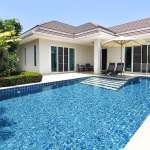 Swimming pool with villa exterior and lawn