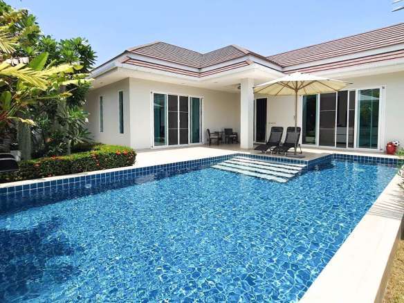 Swimming pool with villa exterior and lawn