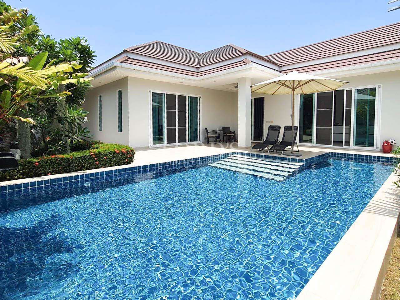 Swimming pool with villa exterior and lawn
