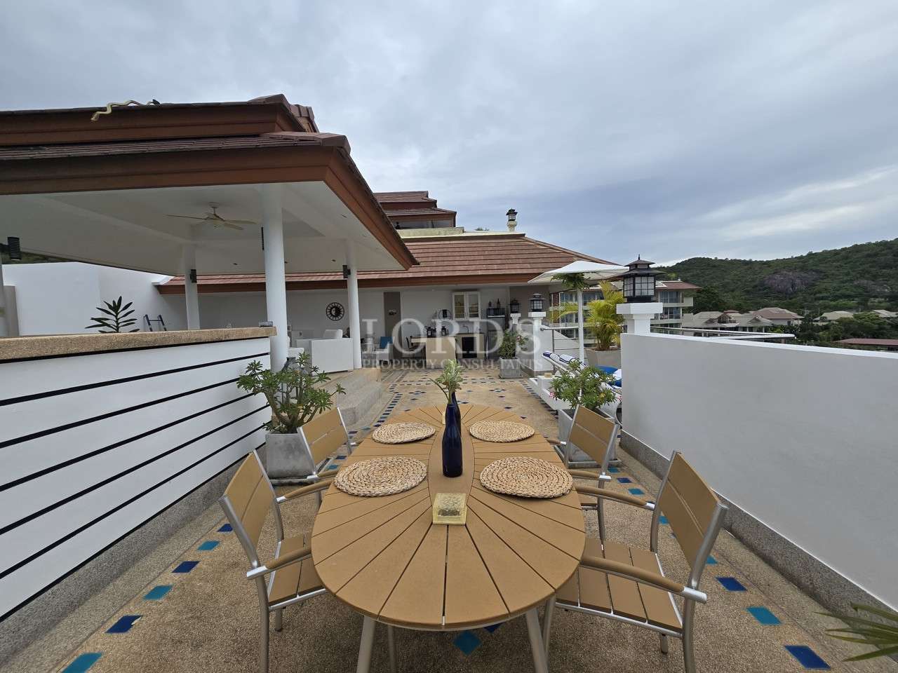 Rooftop terrace dining area with outdoor table and seating overlooking surrounding hills.