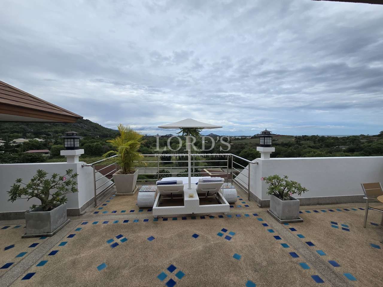 Rooftop terrace with sun loungers and umbrella overlooking scenic countryside views.