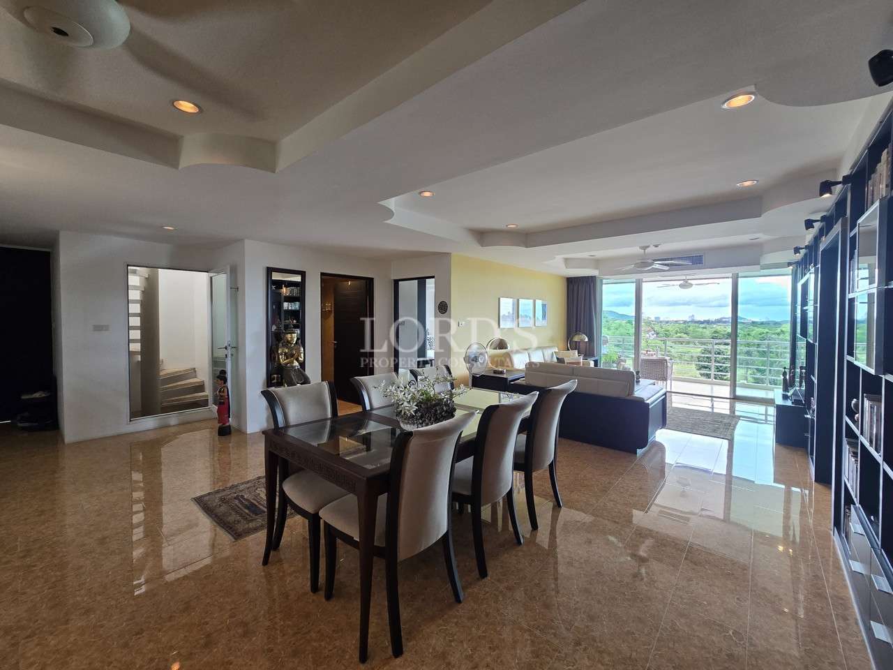 Spacious open-plan living and dining area with balcony views and modern furnishings.