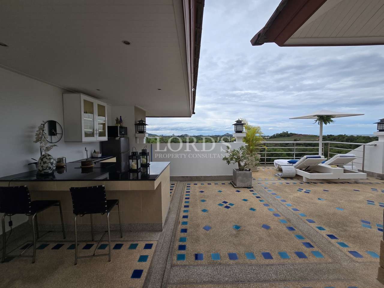 Rooftop terrace with outdoor kitchen, lounge chairs, and scenic countryside views.