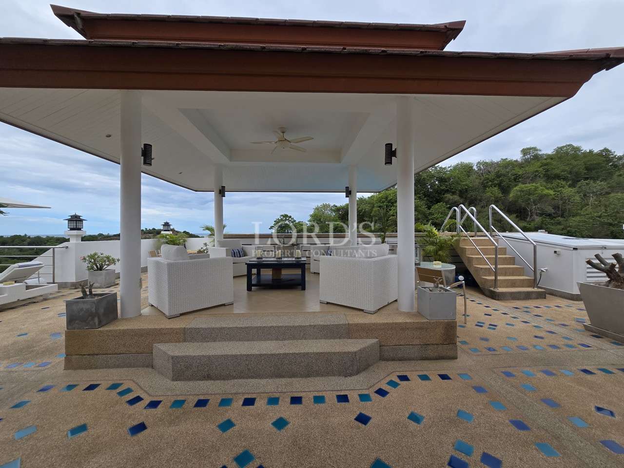 Covered outdoor pavilion with seating area overlooking landscaped surroundings.