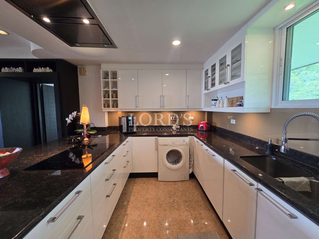 Modern U-shaped kitchen with white cabinets, black countertops, and built-in appliances.