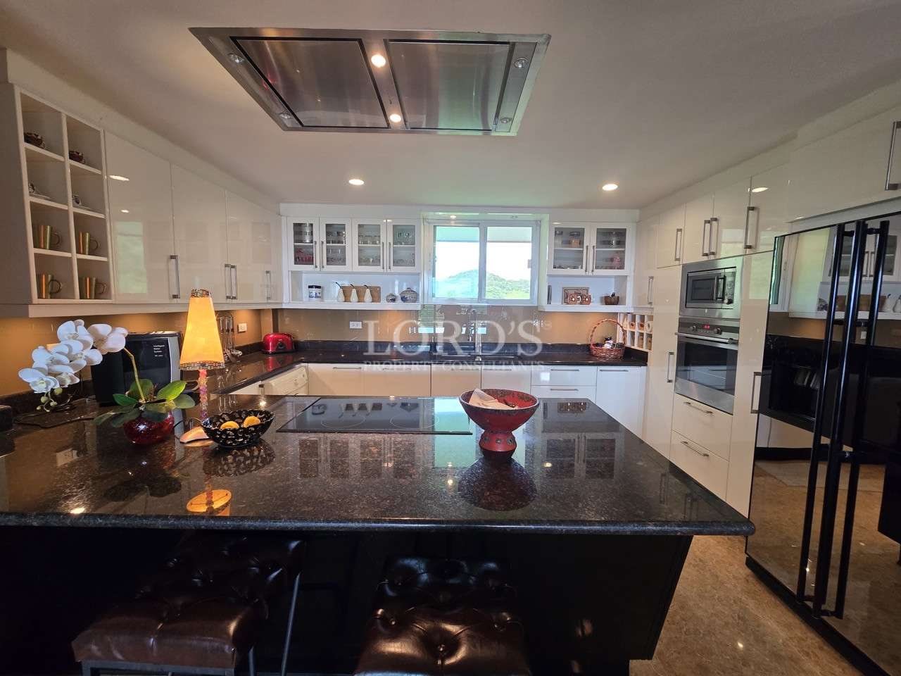 Spacious modern kitchen with island, white cabinets, and black stone countertops.
