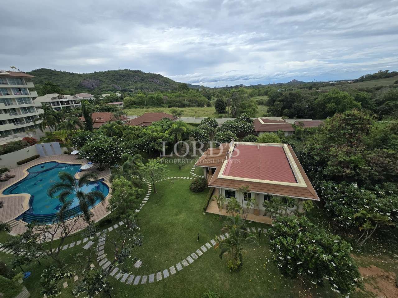 Aerial view of landscaped villa with pool and mountain surroundings.