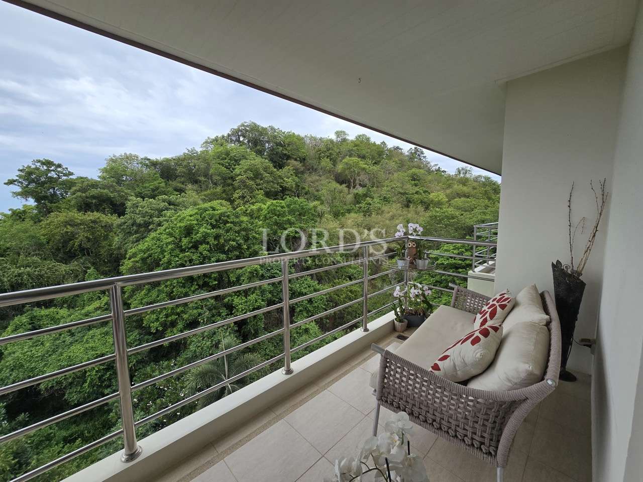 Private balcony with cushioned seating overlooking lush green hillside views.