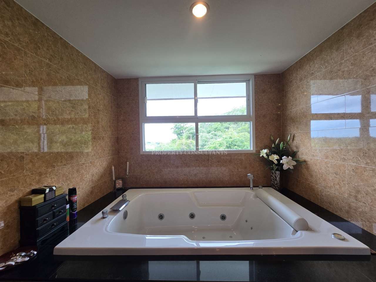 Modern bathroom featuring a built-in jacuzzi bathtub beneath a large window with marble-style wall tiles.