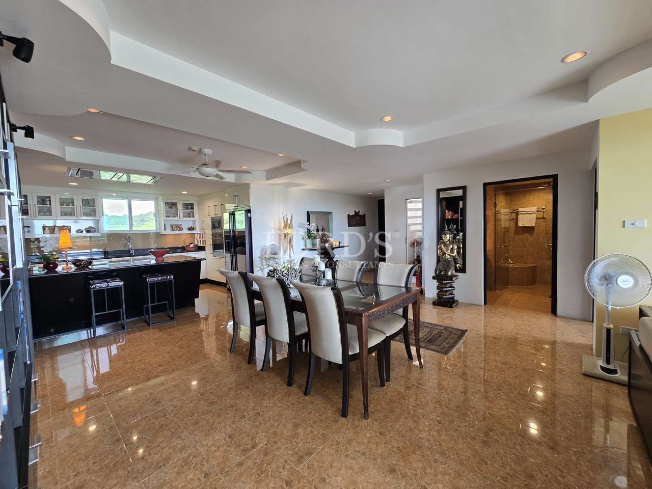 Open-plan dining and kitchen area with modern furnishings, glossy flooring, and island counter.