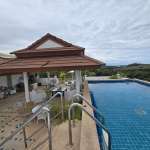 Infinity-style swimming pool with outdoor seating area and scenic hillside views.