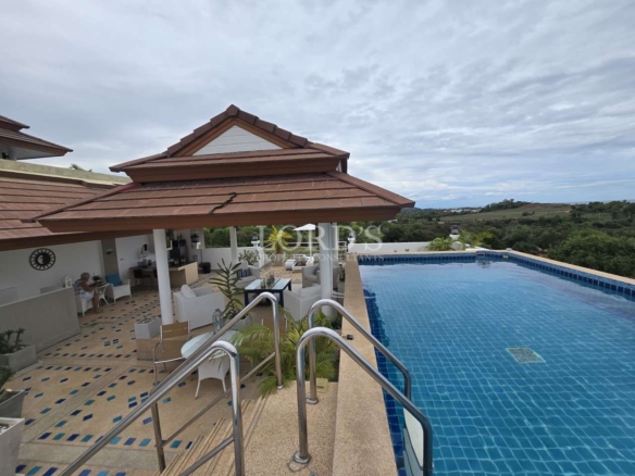 Infinity-style swimming pool with outdoor seating area and scenic hillside views.