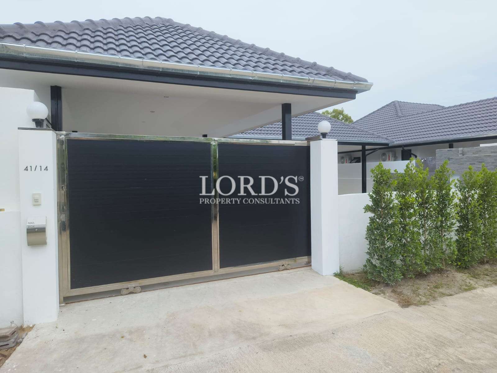 Modern villa entrance with sliding metal gate and covered carport