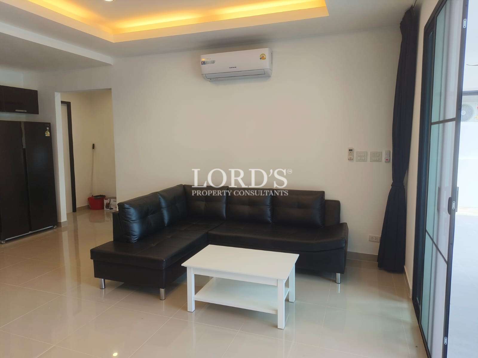 Modern living room with black L-shaped sofa, white coffee table, and sliding glass door.
