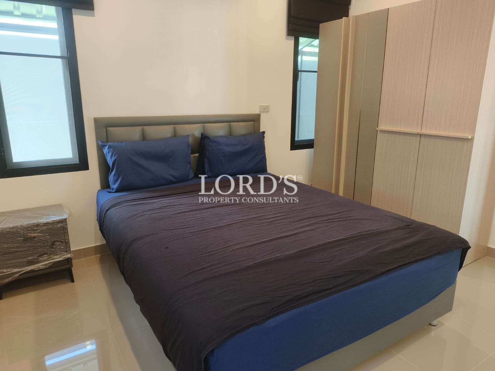 Modern bedroom with double bed, blue bedding, wardrobe, and two windows.